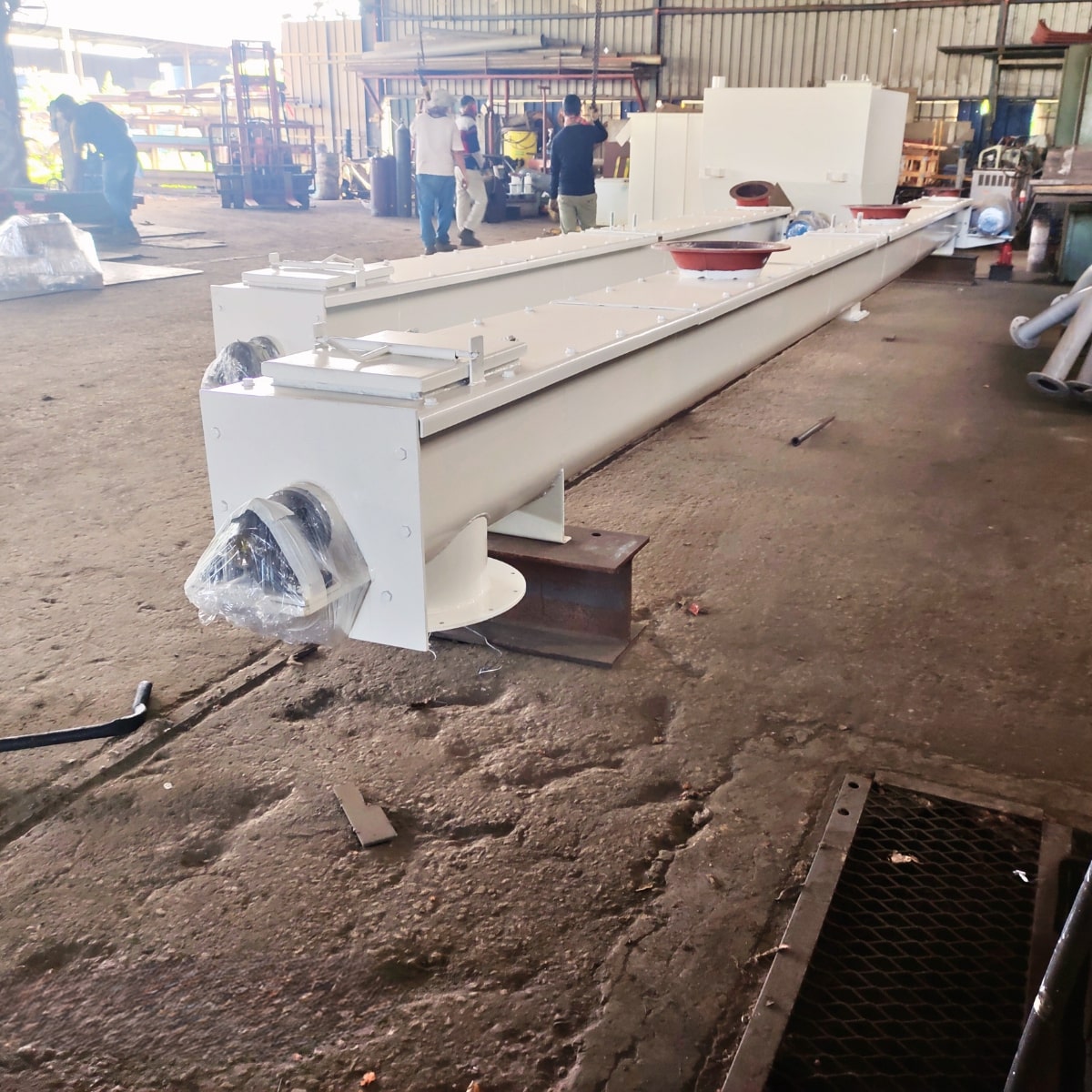A screw/auger conveyor system in a processing plant moves semi-solid materials.