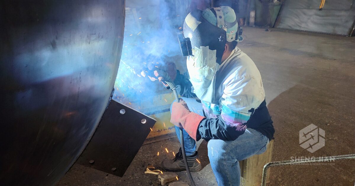 A worker welding a pipe segment in preparation for pipework installation.