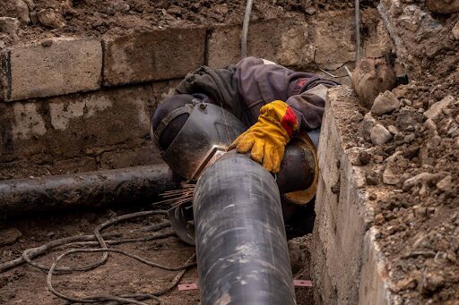 A worker welding a section of industrial piping.