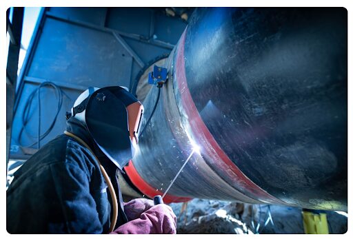An engineer welding a pipe segment.